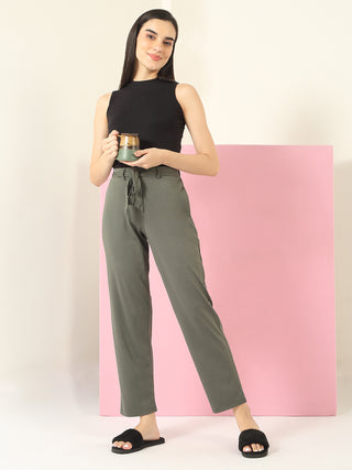 A woman poses wearing a black sleeveless top and olive green pants with a tie waist.