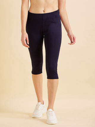 Women wearing navy blue capri leggings and white sneakers, standing with her hands at her side.