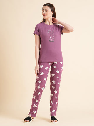 A woman poses wearing a plum-colored pajama set with a star print.