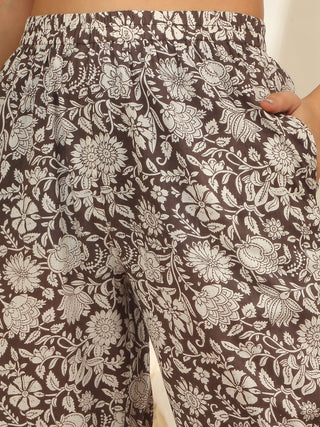 Women's brown floral print sleep pants, similar to the previous image but with a closer view of the pants' fabric and a hand in the pocket.