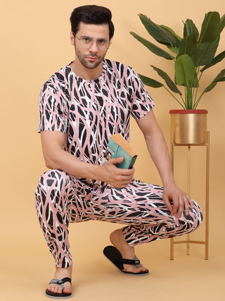 A man in white and blue printed sleepwear sits on a chair while looking at a tablet.