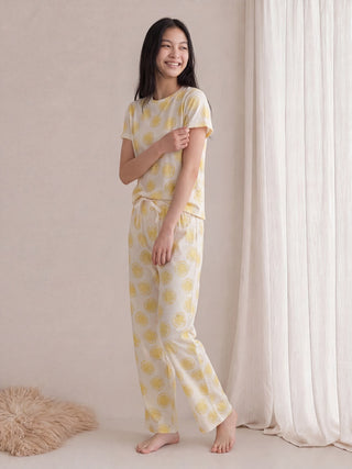 A woman in lemon-print pajamas sits on a beige sofa.