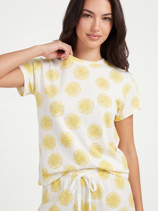 Woman in a white t-shirt with a lemon print, holding the collar of her shirt.