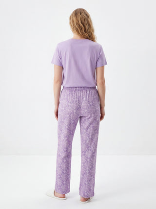 Women wearing light purple patterned pajama pants and a light purple t-shirt, viewed from the back.
