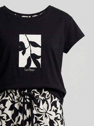Women's black t-shirt with a floral print and white "Les Fleurs" text, paired with black and white floral patterned pajama pants.