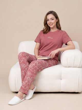 Women sitting on a chair, wearing a pink pajama set with a floral print.