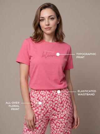 A woman in a pink t-shirt with a typographic print and pink floral pajama pants with an elasticated waistband.