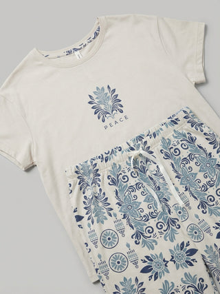 Women's beige t-shirt with a blue floral print and "Peace" text, paired with matching printed pajama shorts, with the print on the shorts being more intricate and detailed than on the t-shirt.