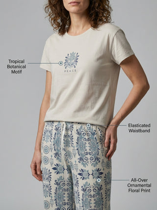 Women in light beige t-shirt with a tropical botanical motif and patterned pajama pants in blue and beige.