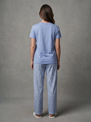 Women in light blue printed pajamas and white slippers, standing from the back.