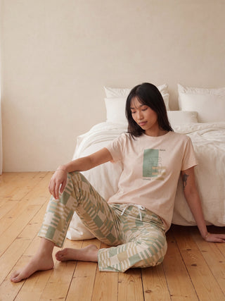 Women's pajama set with a beige t-shirt and patterned pants, posing from the back.