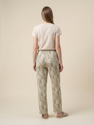 Women's pajama set with a beige t-shirt and patterned pants, posing from the back.