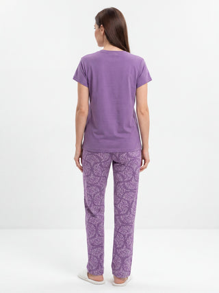 Women in a back view pose, wearing a lavender short-sleeve t-shirt and matching lavender pants with a white swirly print.