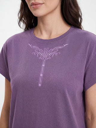 A woman in a purple t-shirt with a printed design, and three buttons.