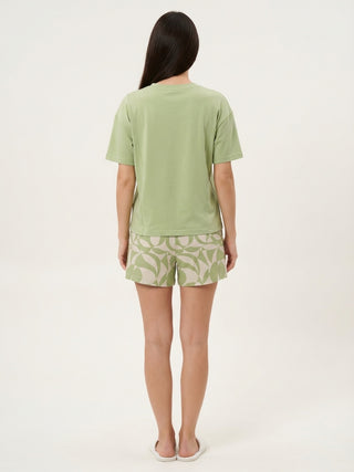 Women in a back view pose wearing a light green t-shirt and light beige shorts with a geometric green print.
