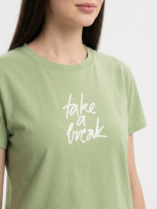 A woman is posing in a light green t-shirt with the text "take a break" printed in white.