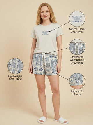 Women in a neutral pose wearing beige t-shirt with minimal floral print on chest and matching patterned shorts with elasticated waistband, lightweight, soft fabric and regular fit.