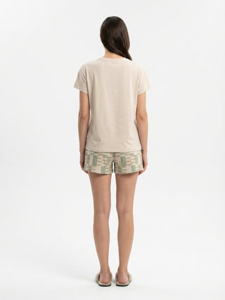 Women wearing a tan t-shirt and green and beige checkered shorts.