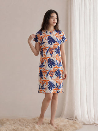 Women's cream short-sleeve midi dress with a navy and rust tropical botanical print, featuring a round neckline, relaxed fit, and side seam pockets.