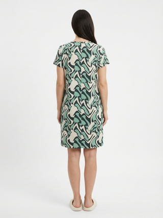 Women wearing a short-sleeved, knee-length dress with an abstract green, black, and cream print, standing from a back view.