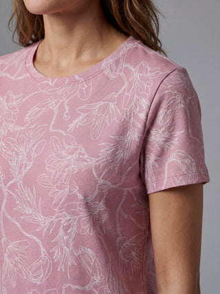 Women in a close-up shot wearing a pink t-shirt with a white floral print.