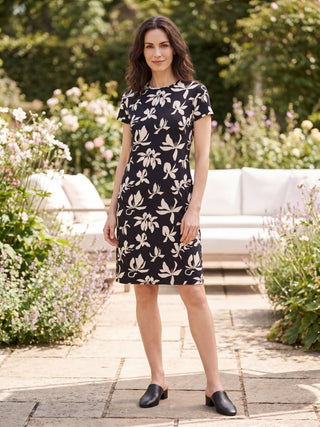 A woman models a black floral print t-shirt dress with black mule shoes.