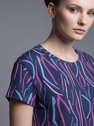 A woman in a navy blue t-shirt with a pink and blue abstract print.