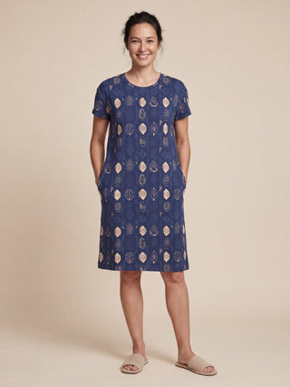 Women in a blue, printed knee-length sleep dress, standing with hands in pockets.