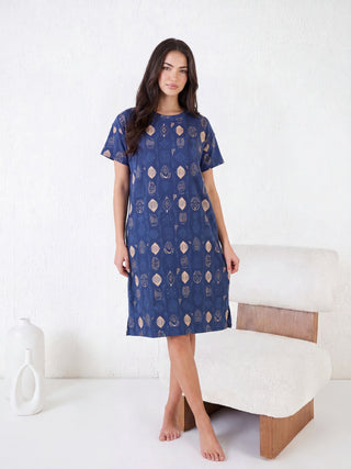Women's blue sleep dress with a geometric print, posing standing in front of a chair.
