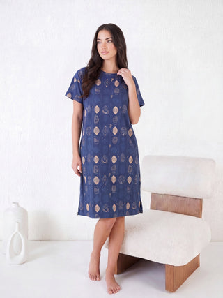 Woman standing in a short-sleeved, knee-length navy blue sleep dress with a tan geometric print, a subtle variation from the previous image's pattern.