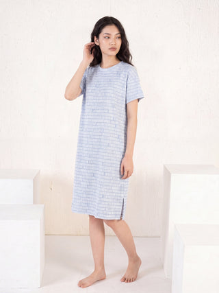 Women in a pale blue patterned nightdress and white slippers posing in a studio shot.