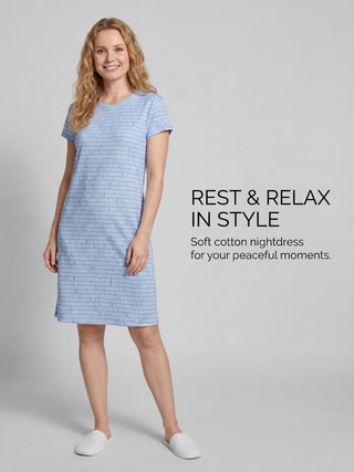 Women in a pale blue patterned nightdress and white slippers posing in a studio shot.