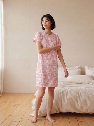 Women wearing a pink short-sleeve t-shirt dress with a geometric print, standing outdoors on a tiled patio.