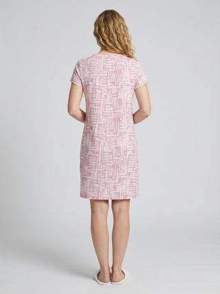 Women, back view, wearing a pink t-shirt dress with a geometric print, and white slides.