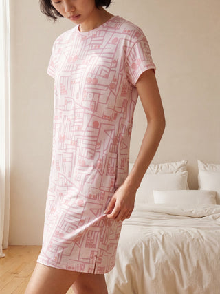 Women, back view, wearing a pink t-shirt dress with a geometric print, and white slides.