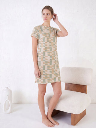 A woman is wearing a short-sleeved geometric print nightgown and white slippers.