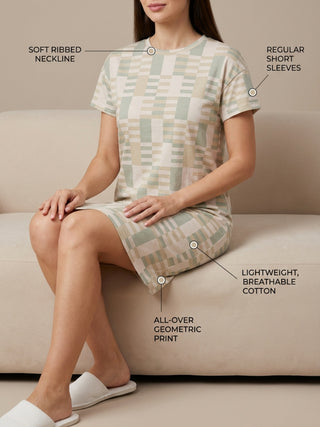 A woman is wearing a short-sleeved geometric print nightgown and white slippers.