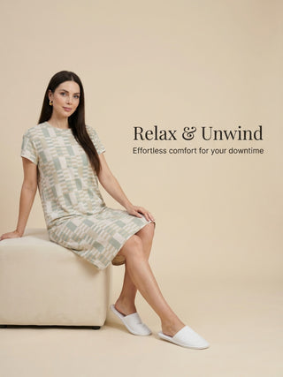 A woman in a light green and beige checkered knee-length dress and white slippers sits on a cream ottoman, with the text "Relax & Unwind" and "Effortless comfort for your downtime" on the right.