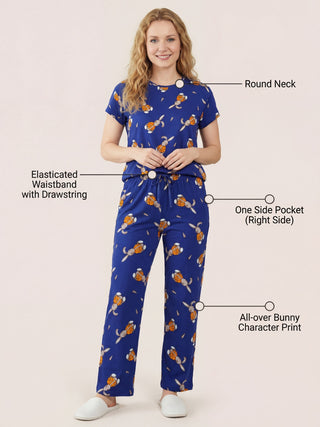 A woman in a blue pajama set with an all-over bunny character print, posing while standing.