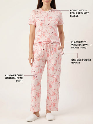 A woman stands wearing pink pajamas with a cartoon bear print.