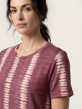A woman in a tie-dye patterned short-sleeve t-shirt.