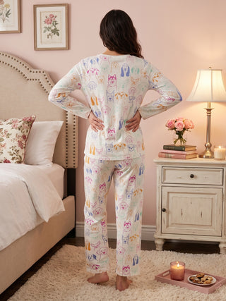 Women in a relaxed pose wear white pajamas with a colorful cartoon dog print.