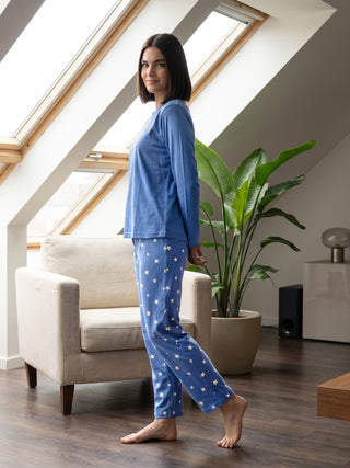 Women in blue star-print pajama set, posing with one leg bent and arm slightly back.