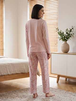 Women wearing pink long-sleeved pajamas with a geometric print, posed from the back, looking out a window.