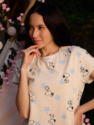 Women's cream sleepwear top with a Snoopy and star print, with the model posing with her hand on her chin.