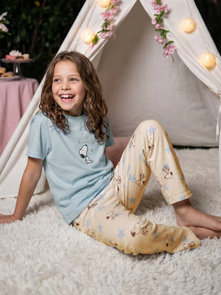 GIRLS sitting on a fluffy white rug wearing light blue Snoopy pajamas.