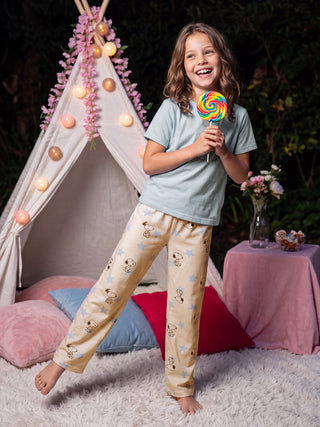 Girls' pajama set featuring a light blue t-shirt and cream-colored pants with a Snoopy and star print, worn by a young girl holding a rainbow lollipop.