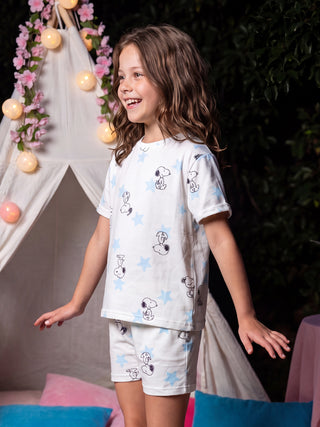 GIRLS white pajama set with Snoopy and star print, standing and smiling.