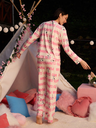 A woman in a pink Snoopy print pajama set posing in a teepee.