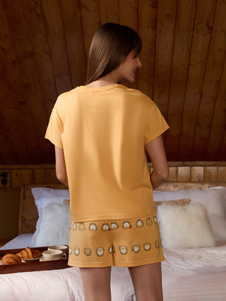 A woman wearing yellow Garfield print sleep shorts and a matching yellow t-shirt.